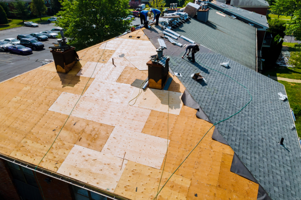 Aerial view of roofers installing or repairing the roof of a commercial building.